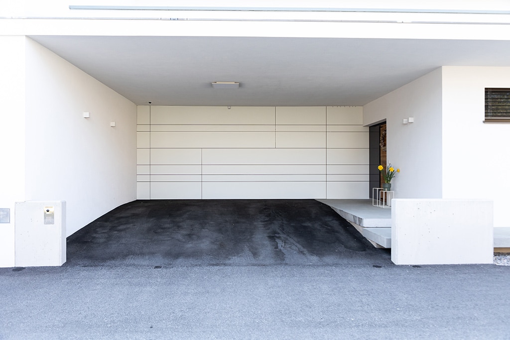 Garagentor, Farbe: weiß, Ansicht von vorne auf Haus mit geschlossenem Garagentor, Aufnahme im Freien bei Sonnenschein