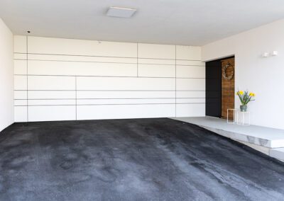 Garagentor geschlossen, Farbe: weiß, Ansicht von schräg seitlich auf Haus mit geschlossenem Garagentor, Aufnahme im Freien bei Sonnenschein